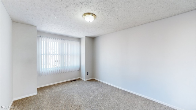 unfurnished room featuring visible vents, a textured ceiling, baseboards, and carpet floors