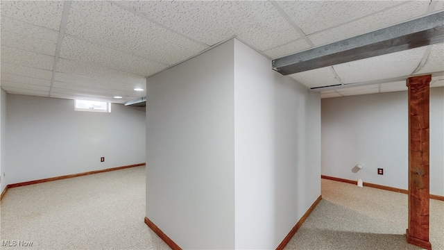 below grade area featuring a paneled ceiling, baseboards, and carpet floors