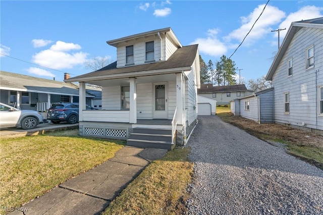 view of front of house with an outbuilding, a garage, a porch, and a front yard