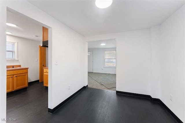 spare room featuring dark wood-type flooring and baseboards