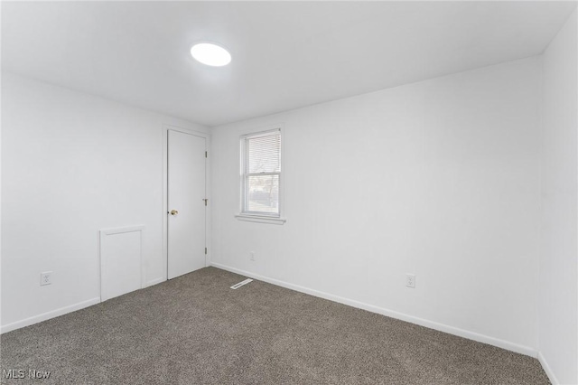 empty room with baseboards and dark colored carpet