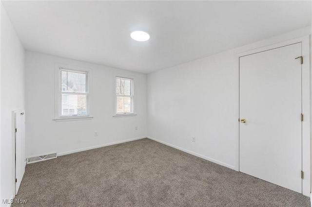 carpeted empty room with visible vents and baseboards