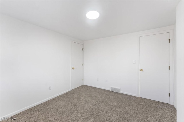 carpeted spare room with visible vents and baseboards