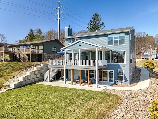 rear view of property featuring a yard, a chimney, stairs, and a patio