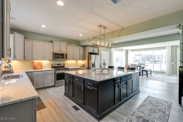 kitchen with visible vents, pendant lighting, a sink, stainless steel appliances, and dark cabinets