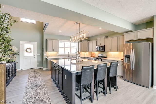 kitchen featuring light wood-style flooring, a kitchen breakfast bar, a kitchen island, stainless steel appliances, and baseboards