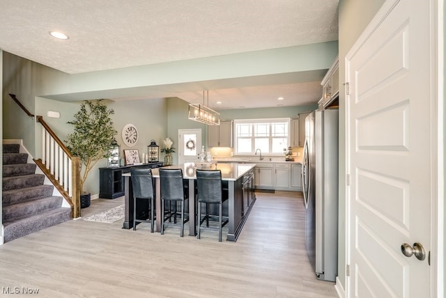 kitchen featuring a kitchen island, freestanding refrigerator, light wood-style floors, a breakfast bar area, and light countertops