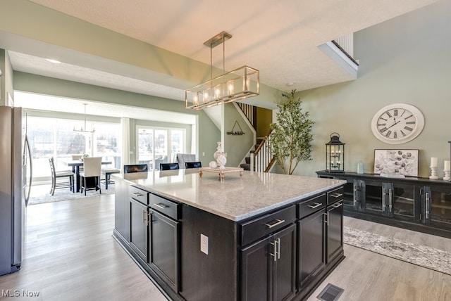 kitchen with light wood-style floors, visible vents, freestanding refrigerator, and a chandelier