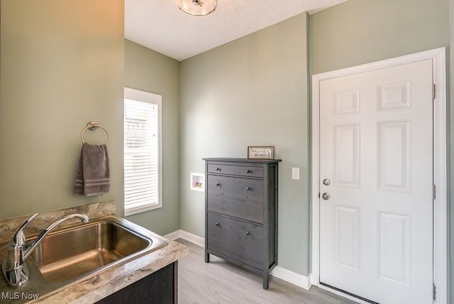 kitchen featuring light wood-type flooring, baseboards, and a sink