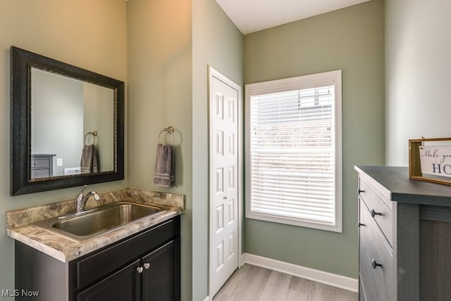 bathroom featuring vanity, wood finished floors, a healthy amount of sunlight, and baseboards