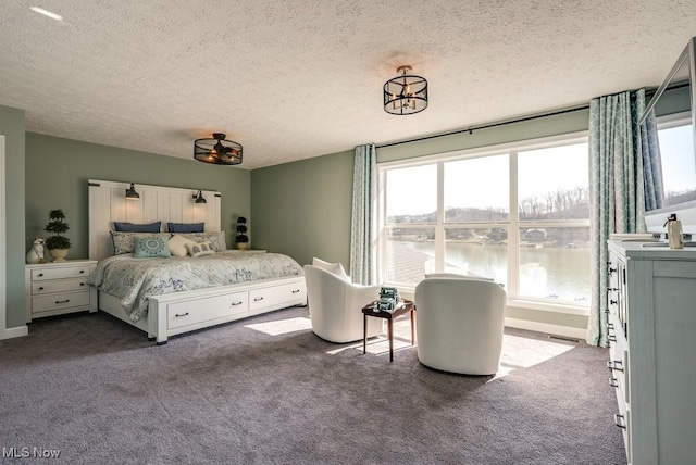 carpeted bedroom with visible vents, a water view, and a textured ceiling