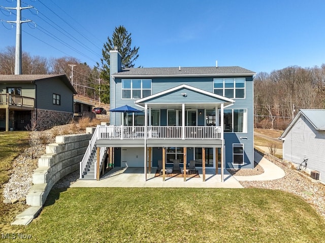 rear view of property featuring stairway, a lawn, a chimney, and a patio