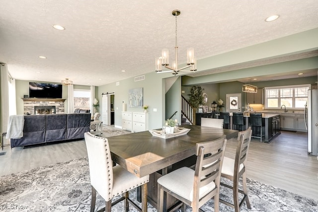 dining room with a chandelier, stairway, a textured ceiling, and light wood-style floors