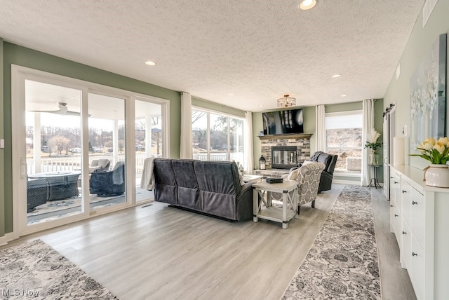 living room featuring a fireplace, recessed lighting, light wood-style floors, and a textured ceiling