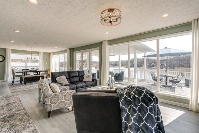 living area featuring a water view, a chandelier, recessed lighting, wood finished floors, and a textured ceiling