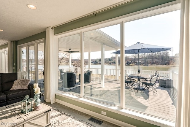 sunroom with visible vents and a water view