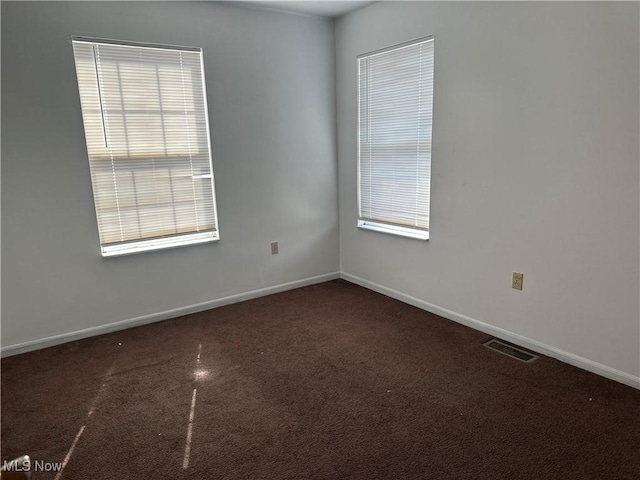 carpeted empty room with visible vents, plenty of natural light, and baseboards