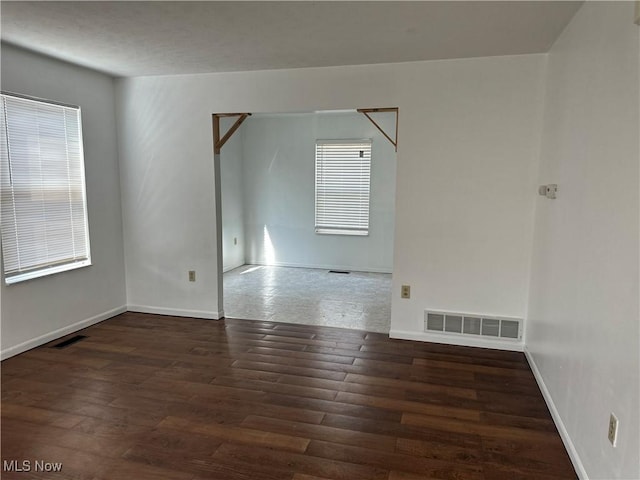 unfurnished room featuring visible vents, baseboards, and wood finished floors