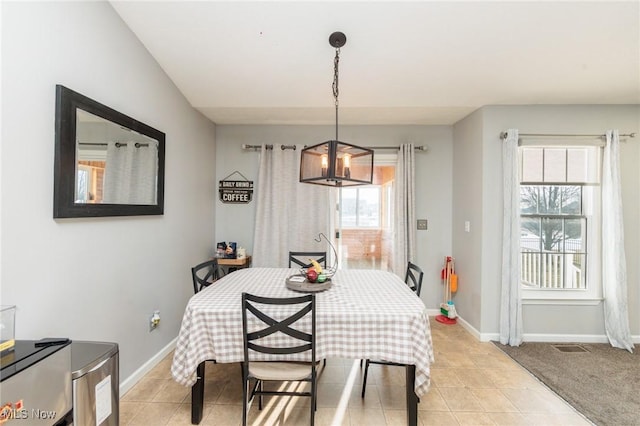 dining room featuring an inviting chandelier, light tile patterned floors, light colored carpet, and baseboards