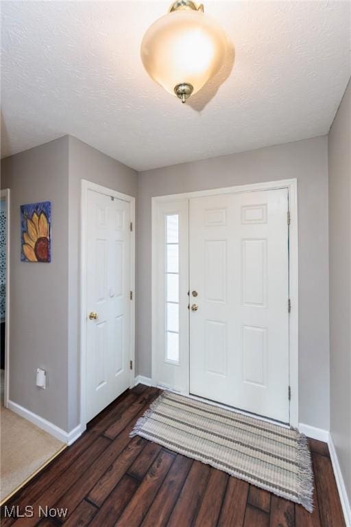 entryway with baseboards, a textured ceiling, and dark wood-style floors