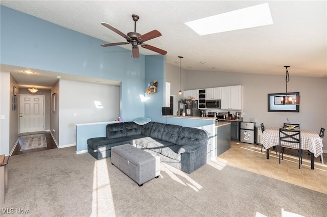 living room featuring high vaulted ceiling, light colored carpet, baseboards, and ceiling fan