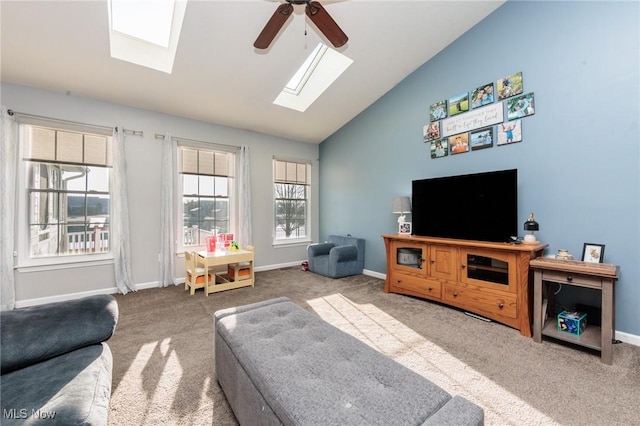 carpeted living room with baseboards, high vaulted ceiling, a skylight, and a ceiling fan