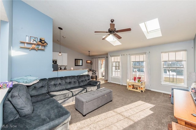 living area featuring lofted ceiling with skylight, carpet floors, a healthy amount of sunlight, and a ceiling fan