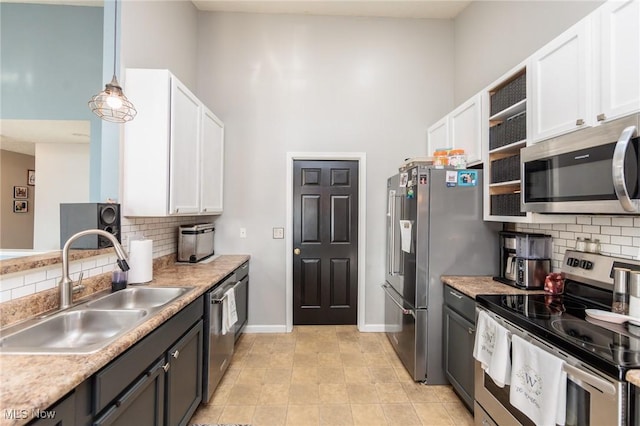 kitchen with appliances with stainless steel finishes, white cabinetry, baseboards, and a sink