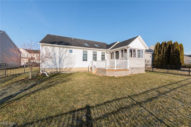 rear view of property featuring a lawn and fence