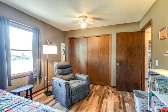 bedroom with ceiling fan, wood finished floors, a closet, and a textured ceiling