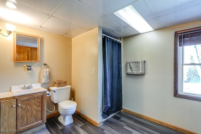 full bathroom featuring a drop ceiling, toilet, wood finished floors, and vanity