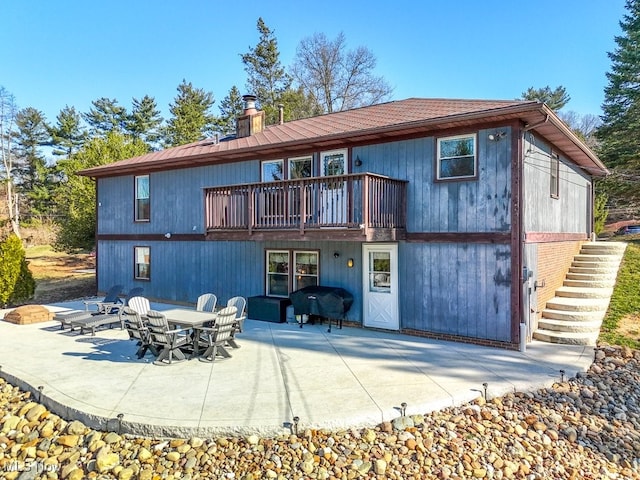 rear view of house featuring a patio, stairway, and a chimney