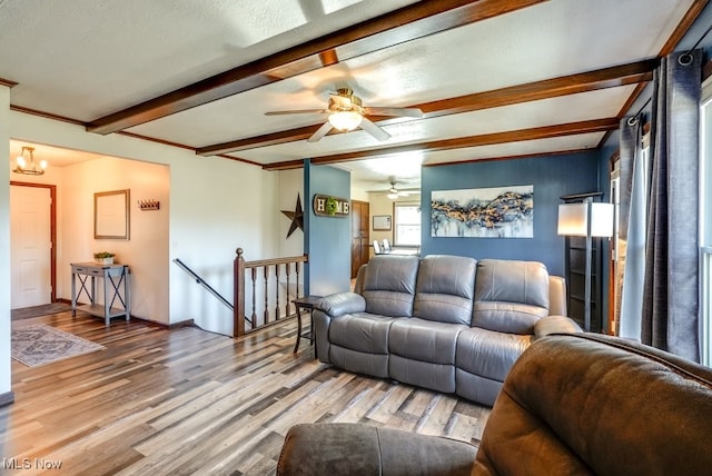 living room featuring beam ceiling, a ceiling fan, baseboards, and light wood finished floors