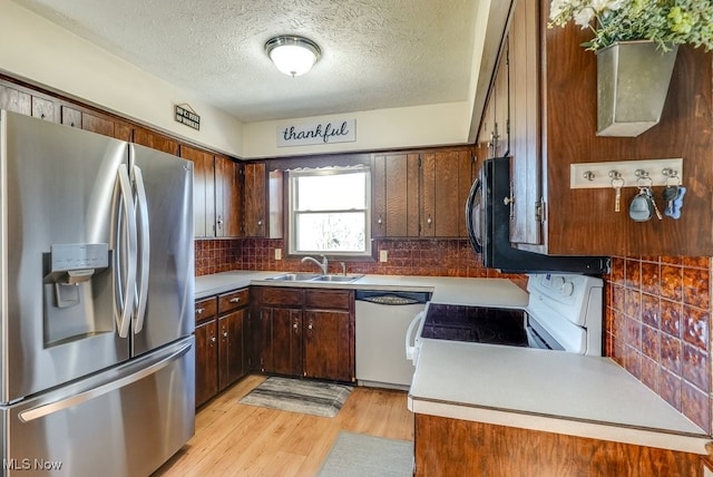 kitchen featuring white appliances, a sink, decorative backsplash, a textured ceiling, and light wood-type flooring