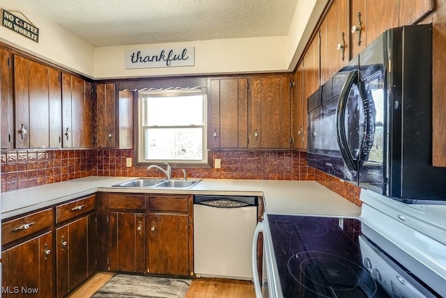 kitchen with dishwashing machine, range with electric stovetop, light countertops, and a sink