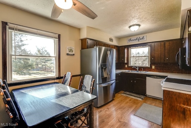 kitchen featuring stainless steel refrigerator with ice dispenser, a sink, light wood-style floors, dark brown cabinetry, and dishwasher