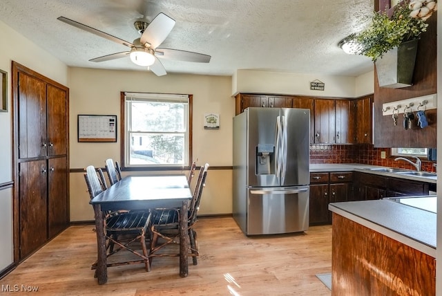 kitchen featuring ceiling fan, stainless steel fridge with ice dispenser, light wood-type flooring, and a sink