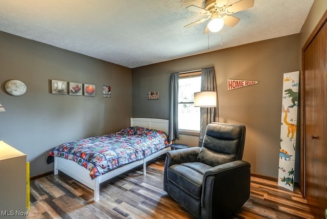 bedroom featuring ceiling fan, wood finished floors, and a textured ceiling