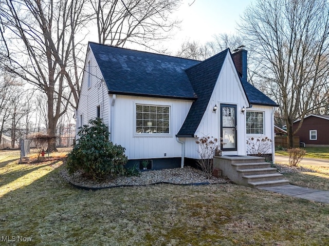 view of front of house featuring a chimney, a front lawn, and a shingled roof