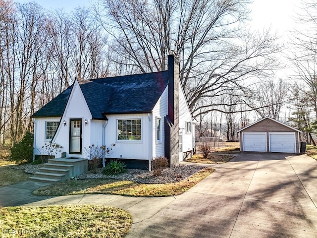 view of front facade with a detached garage, an outdoor structure, a chimney, and a shingled roof