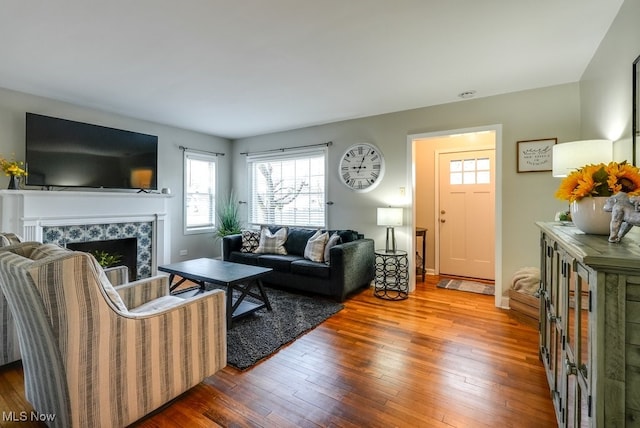 living room with wood-type flooring and a tiled fireplace