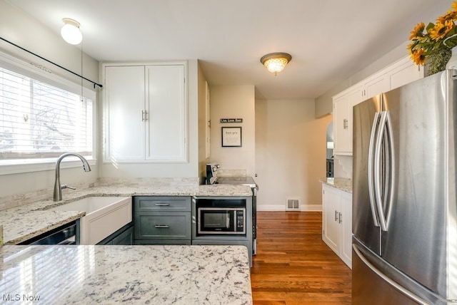 kitchen with visible vents, a sink, freestanding refrigerator, white cabinets, and built in microwave