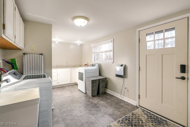 clothes washing area with washer and dryer, baseboards, cabinet space, and heating unit