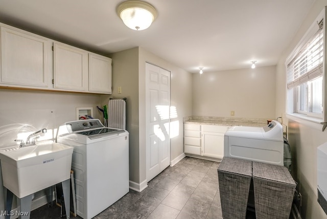 laundry area with cabinet space, independent washer and dryer, baseboards, and a sink