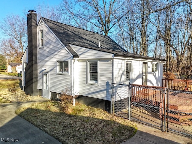 view of side of home featuring a chimney, fence, and a gate