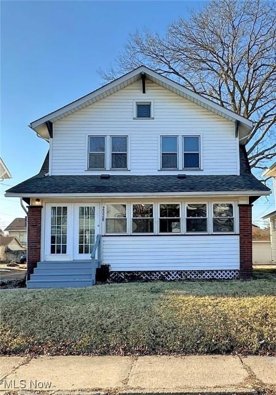 view of front of house featuring entry steps, a front lawn, and brick siding