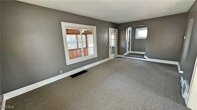 spare room featuring arched walkways, visible vents, carpet floors, and baseboards