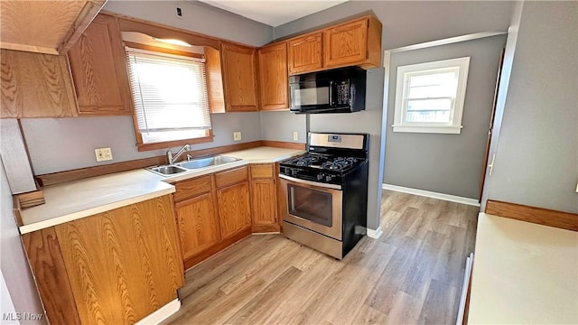 kitchen with a sink, stainless steel gas range, black microwave, and a healthy amount of sunlight