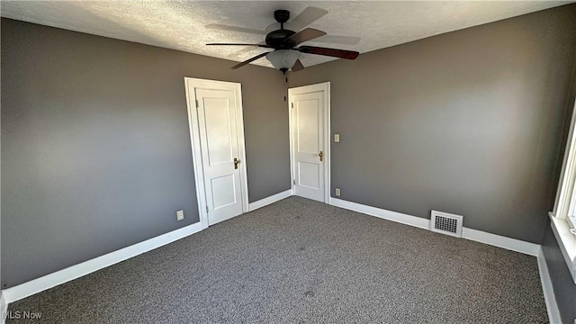 unfurnished room featuring a ceiling fan, visible vents, baseboards, a textured ceiling, and dark colored carpet