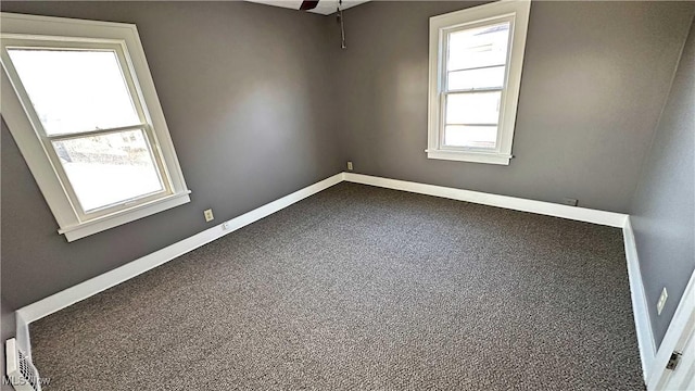 spare room with a ceiling fan and baseboards